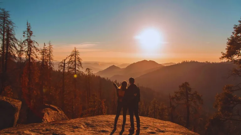Couple watching sunset over forested mountains