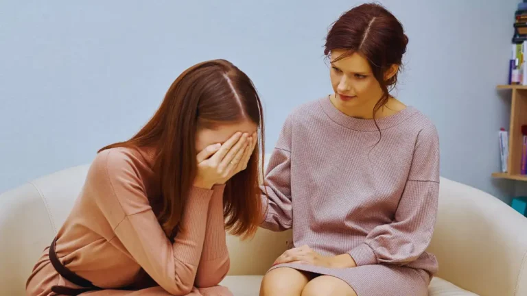 Woman comforting distressed friend on couch