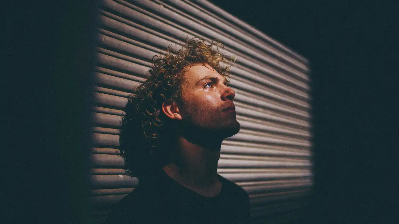Man gazing upward beside a striped wall