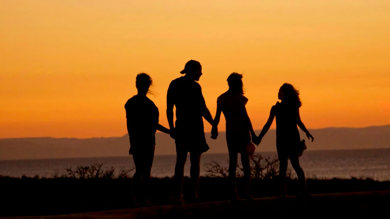 Silhouetted family holding hands at sunset