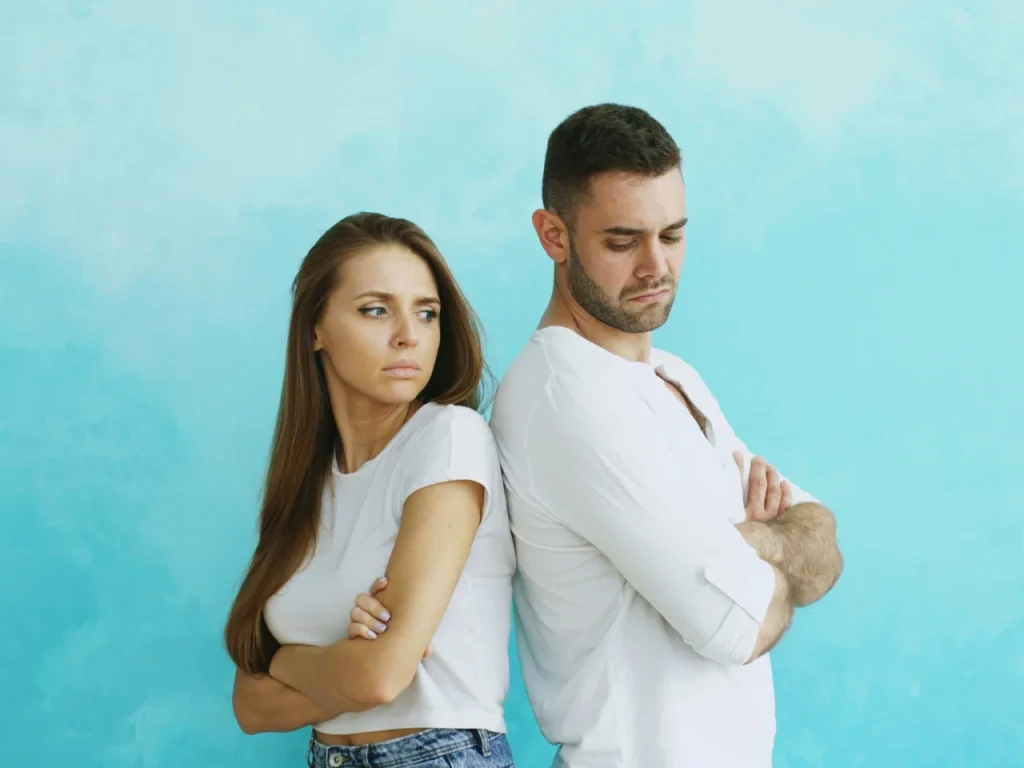 Couple standing back to back with arms crossed, showing signs of contempt