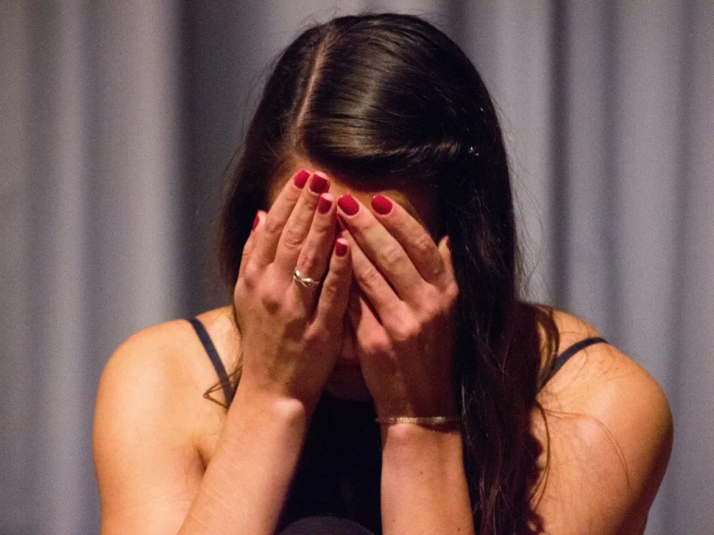Woman covering her face, experiencing CPTSD symptoms