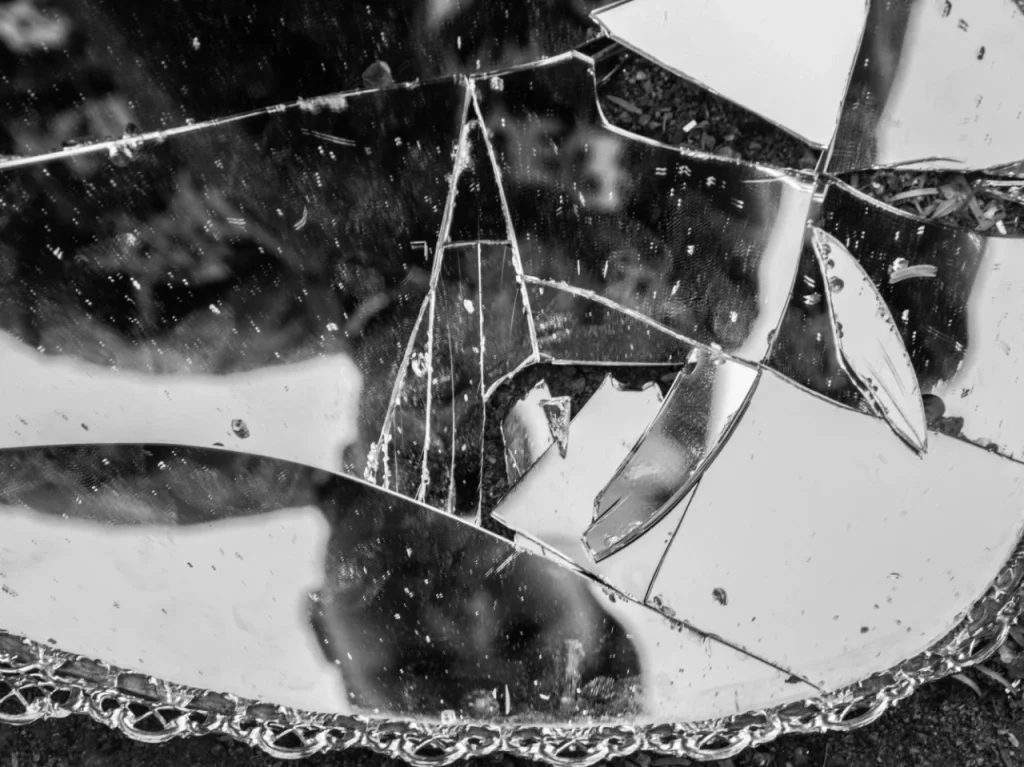 Broken mirror on a sidewalk, representing the difference between PTSD and CPTSD