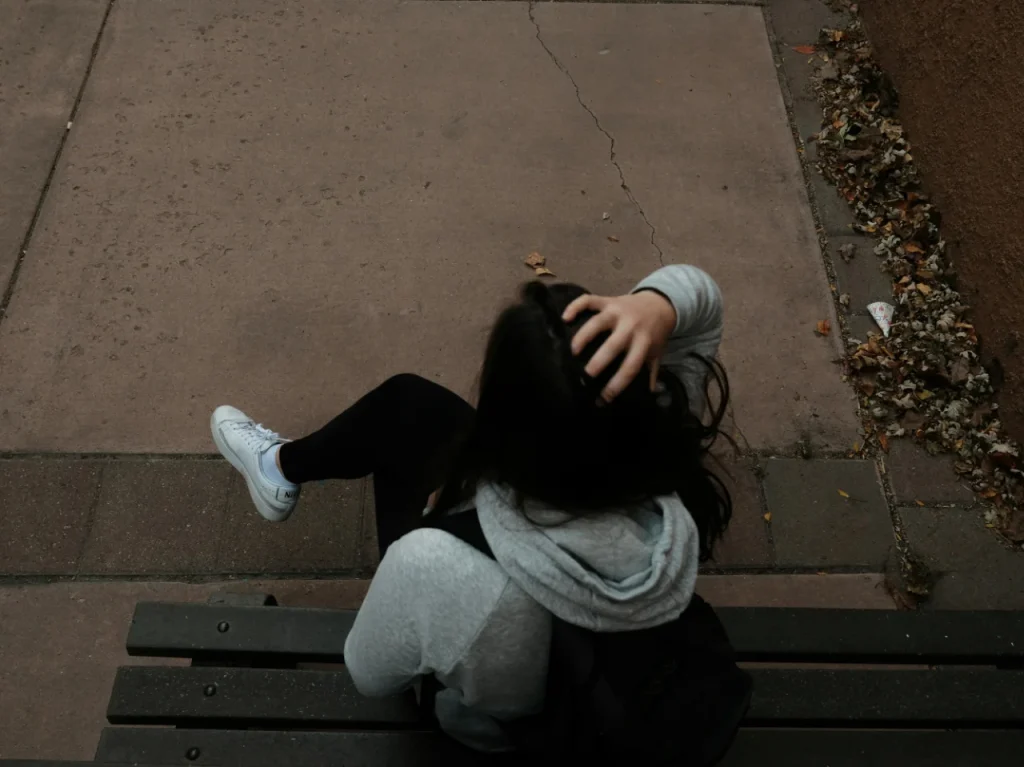 Person sitting alone on a bench, reflecting on the causes of complex trauma