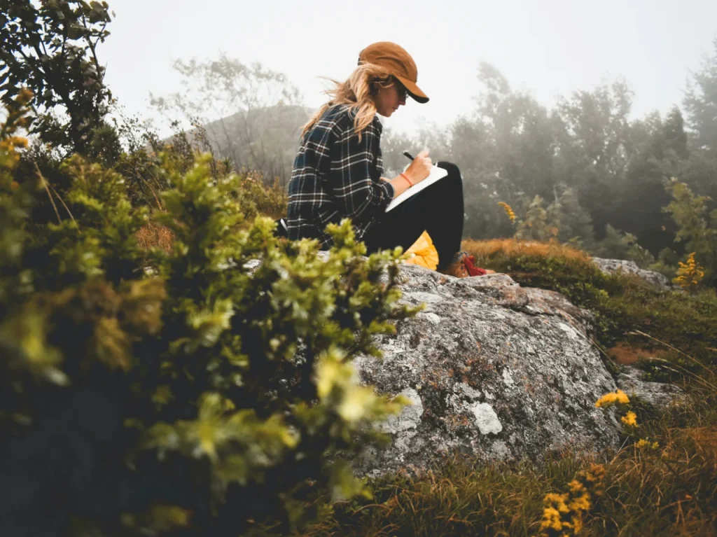 Woman writing in a journal outdoors as part of healing from CPTSD