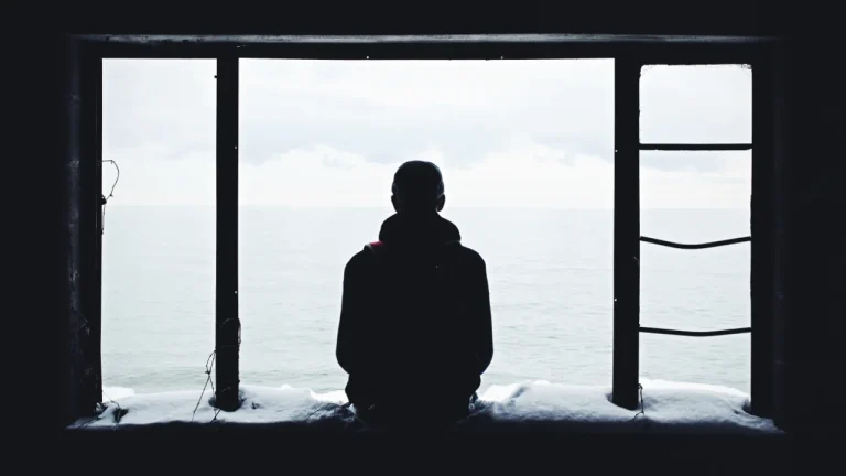 Person looking out a window on a grey day, feeling the winter blues
