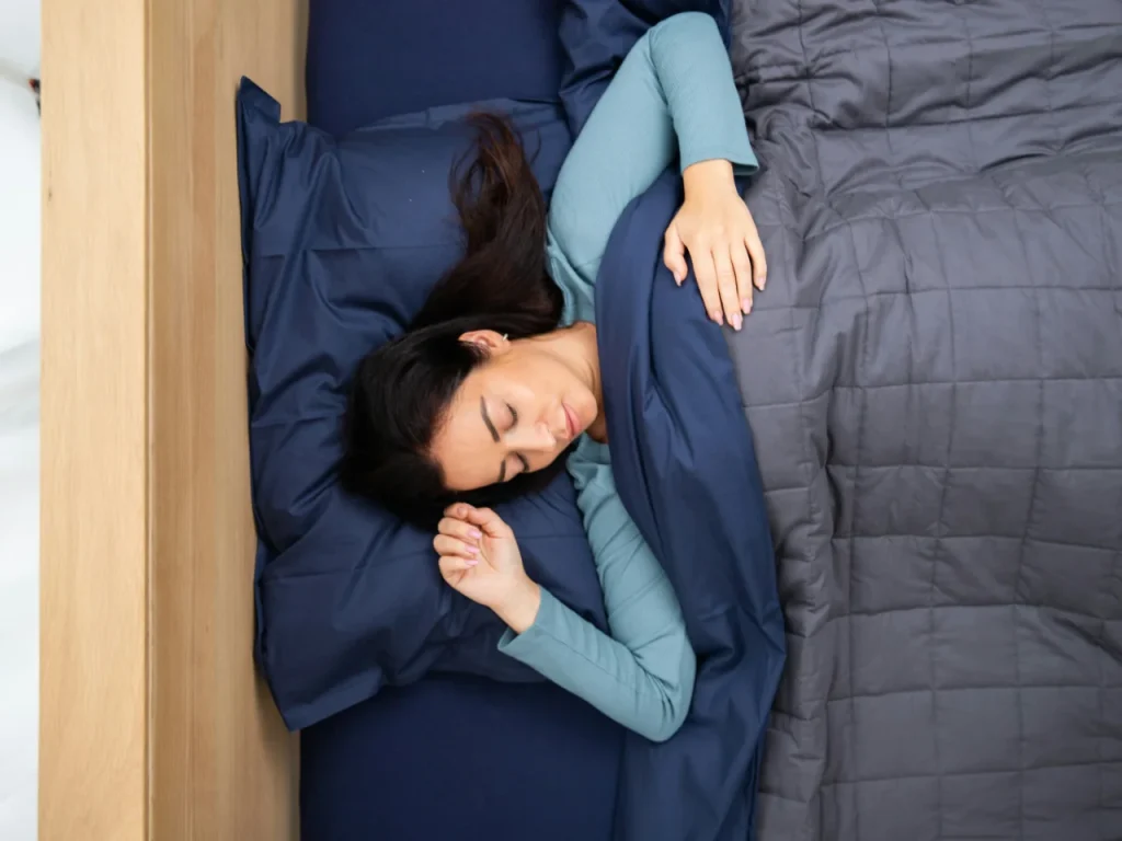 Woman sleeping in bed, a common sign of oversleeping with SAD symptoms